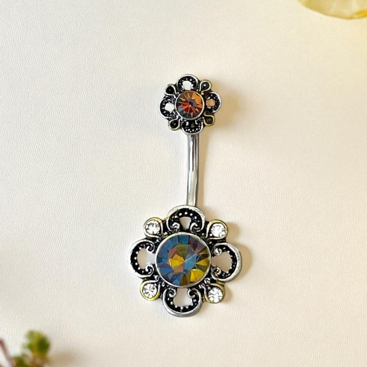 Decorative belly button ring with floral design on a light background