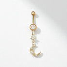 Gold belly button ring with a moon and star design on a white background
