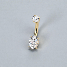 Gold belly button ring with clear gemstones on a gray background
