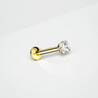 Gold flat back earring with a clear gemstone on a light gray background