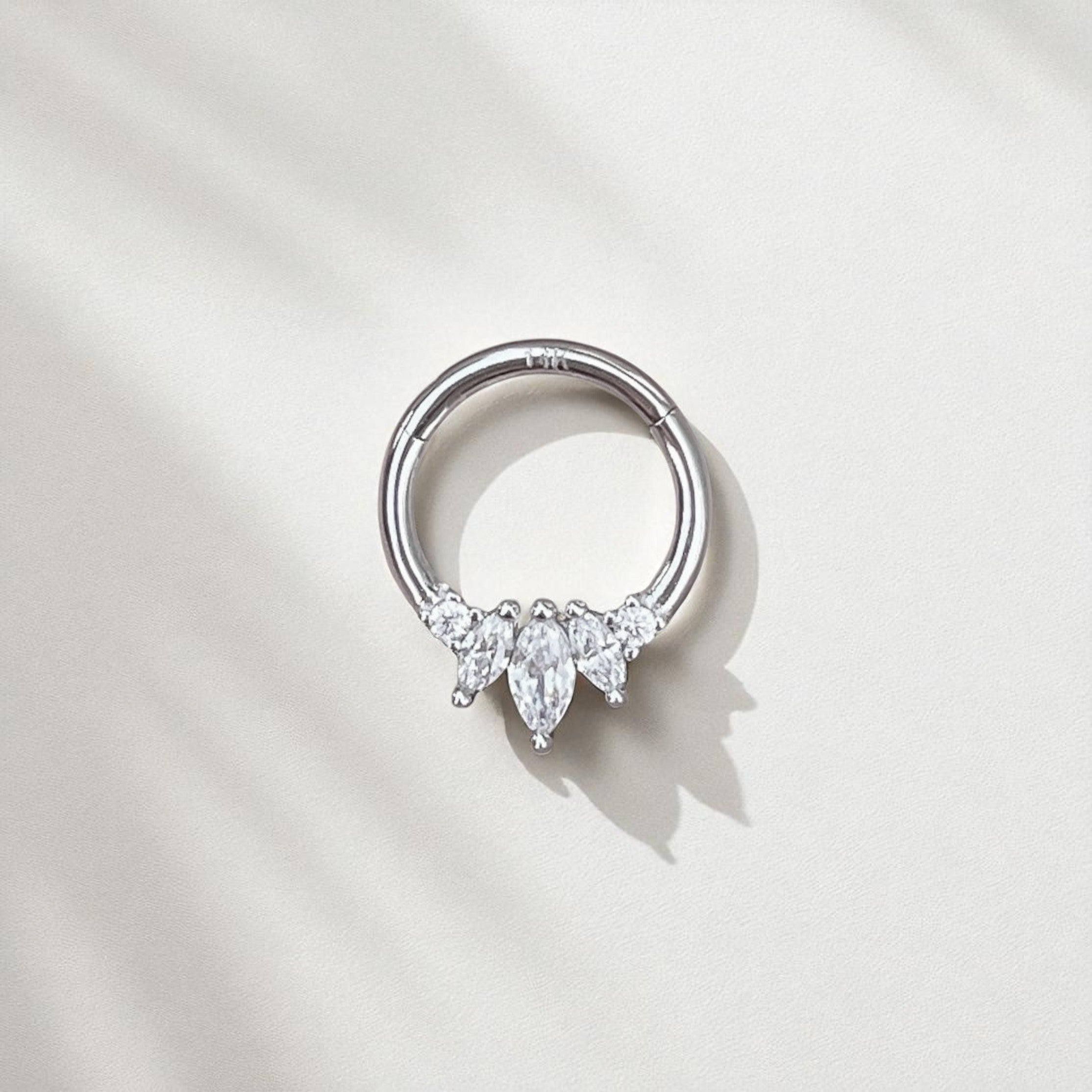 Silver ring with three teardrop-shaped gemstones on a light gray background