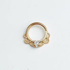 Gold daith earring with decorative design and clear gemstone on a white background