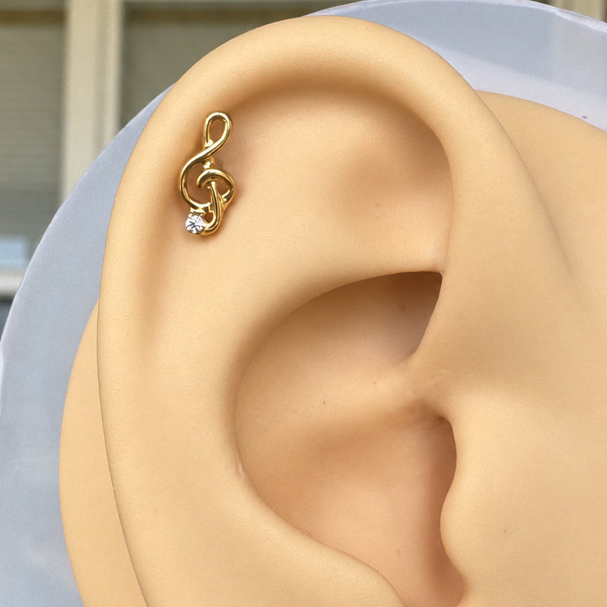 Musical note flat back stud displayed on a silicone ear.