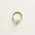 Gold daith earring with clear gemstones on a light beige background