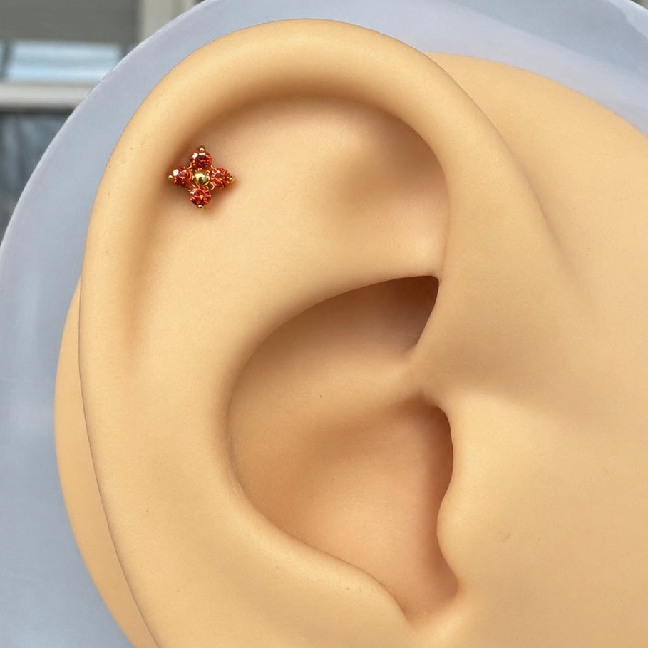 Flat back stud with four CZs in red, on a silicone ear for display.