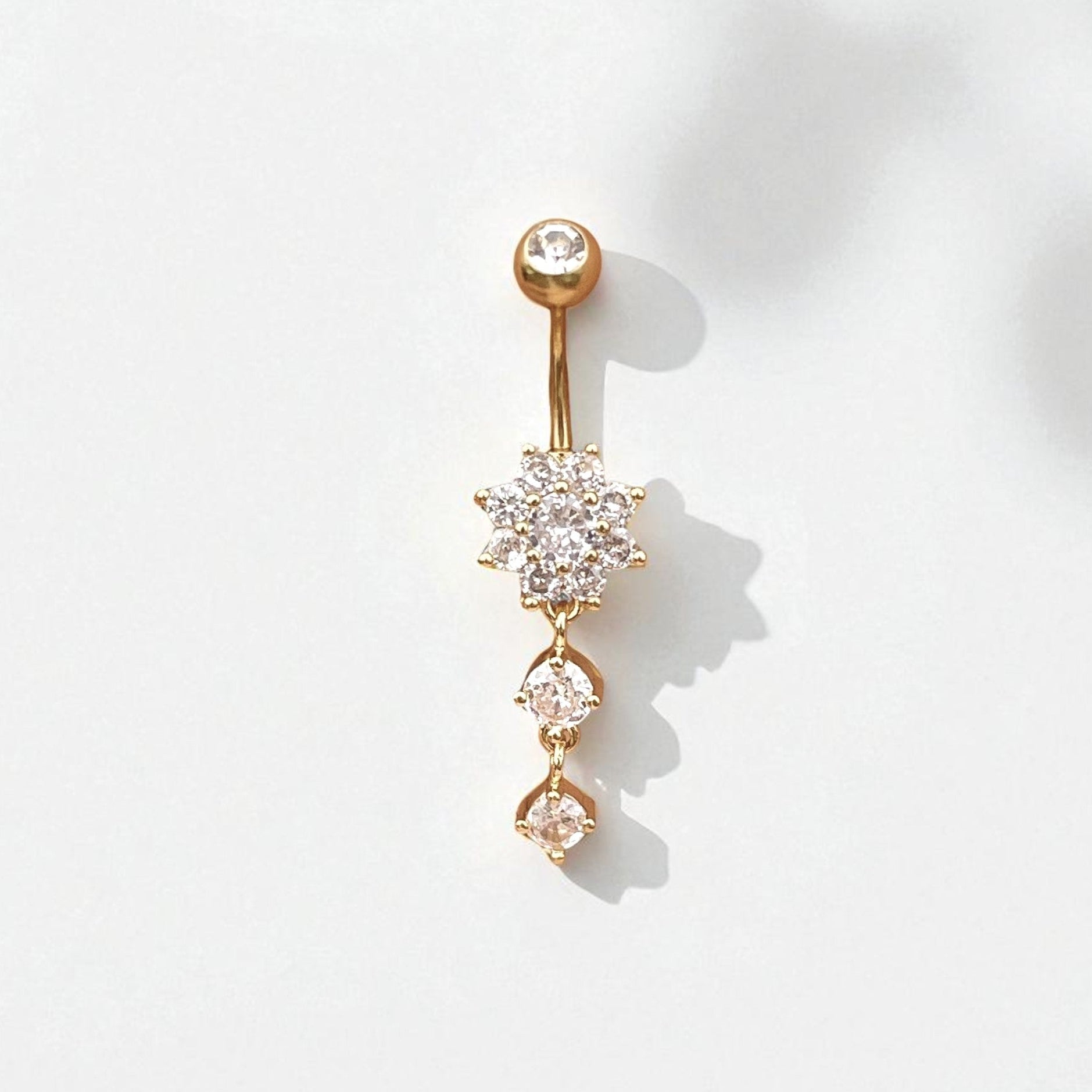 Gold belly button ring with clear gemstones on a white background