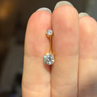 Gold belly button ring with clear moissanite gemstones on a hand