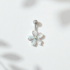 Flower-shaped belly button ring on a light pink background