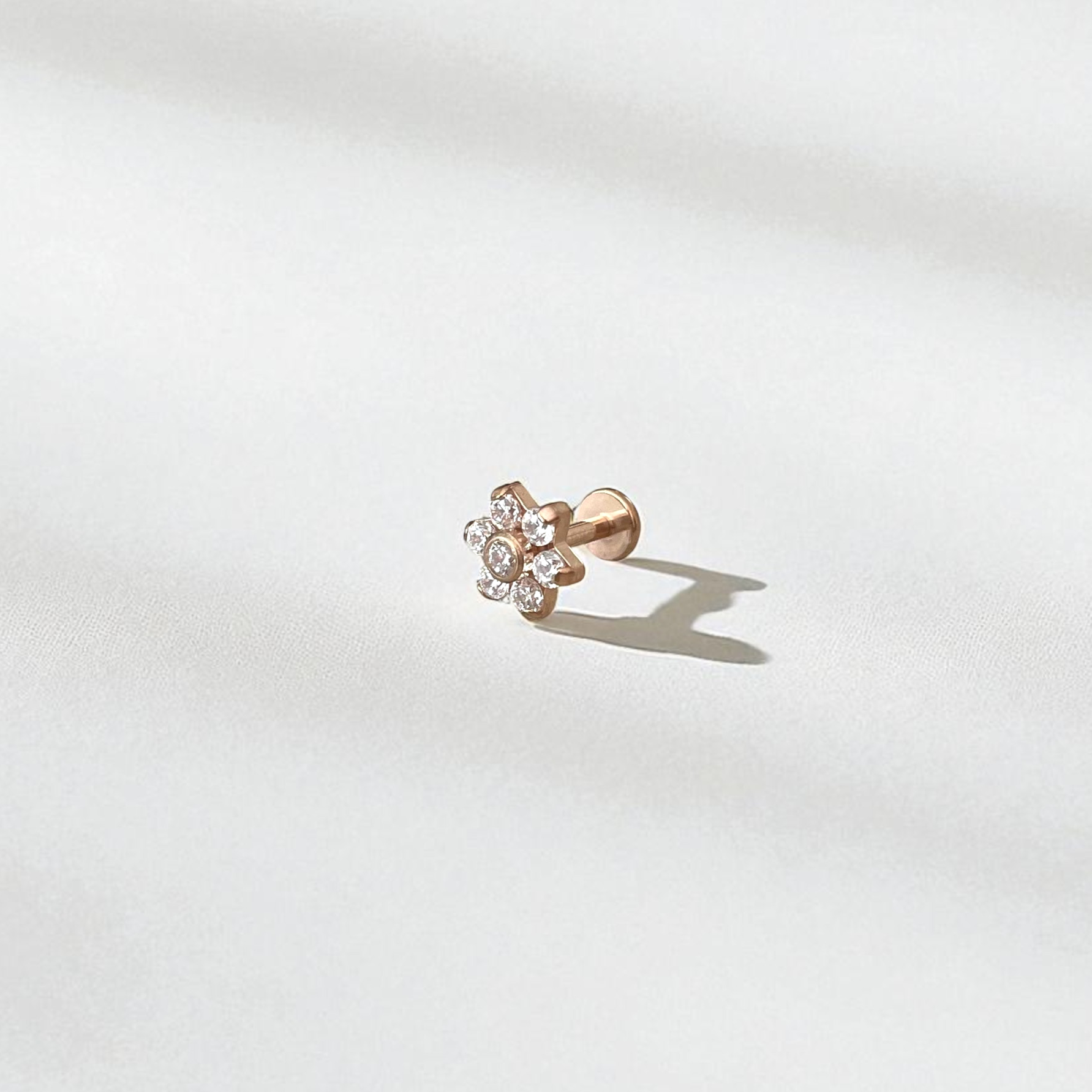 Rose gold earring with floral design on a light gray background