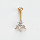 Gold belly button ring with clear gemstones on a light gray background