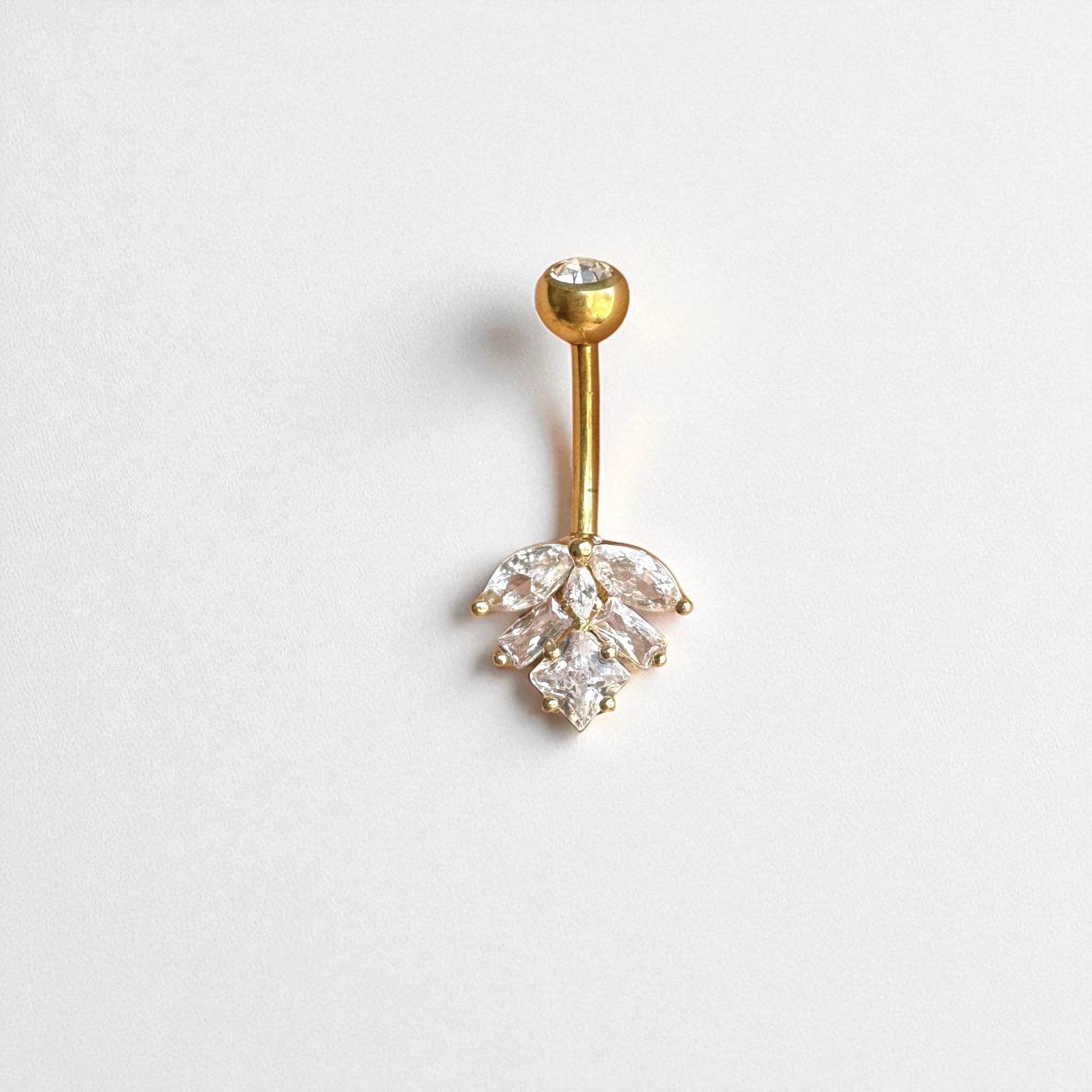 Gold belly button ring with clear gemstones in a leaf shape on a white background