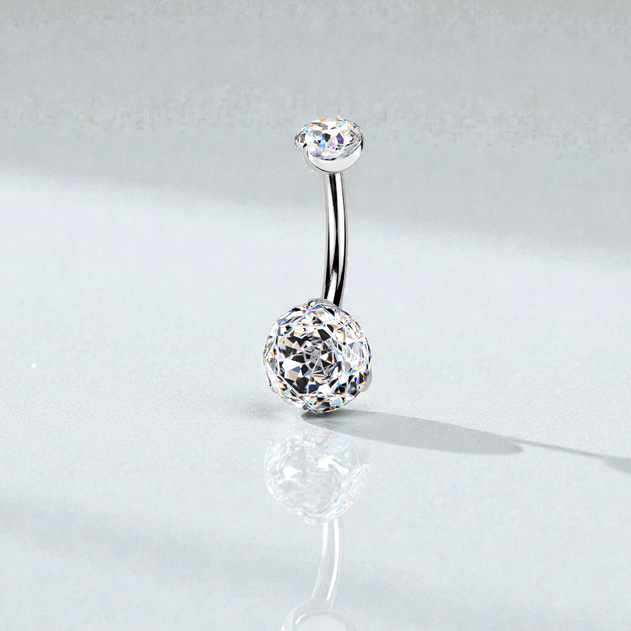 Silver belly button ring with clear gemstones on a light gray background