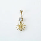 Gold belly button ring with spider design and clear gemstone on a white background