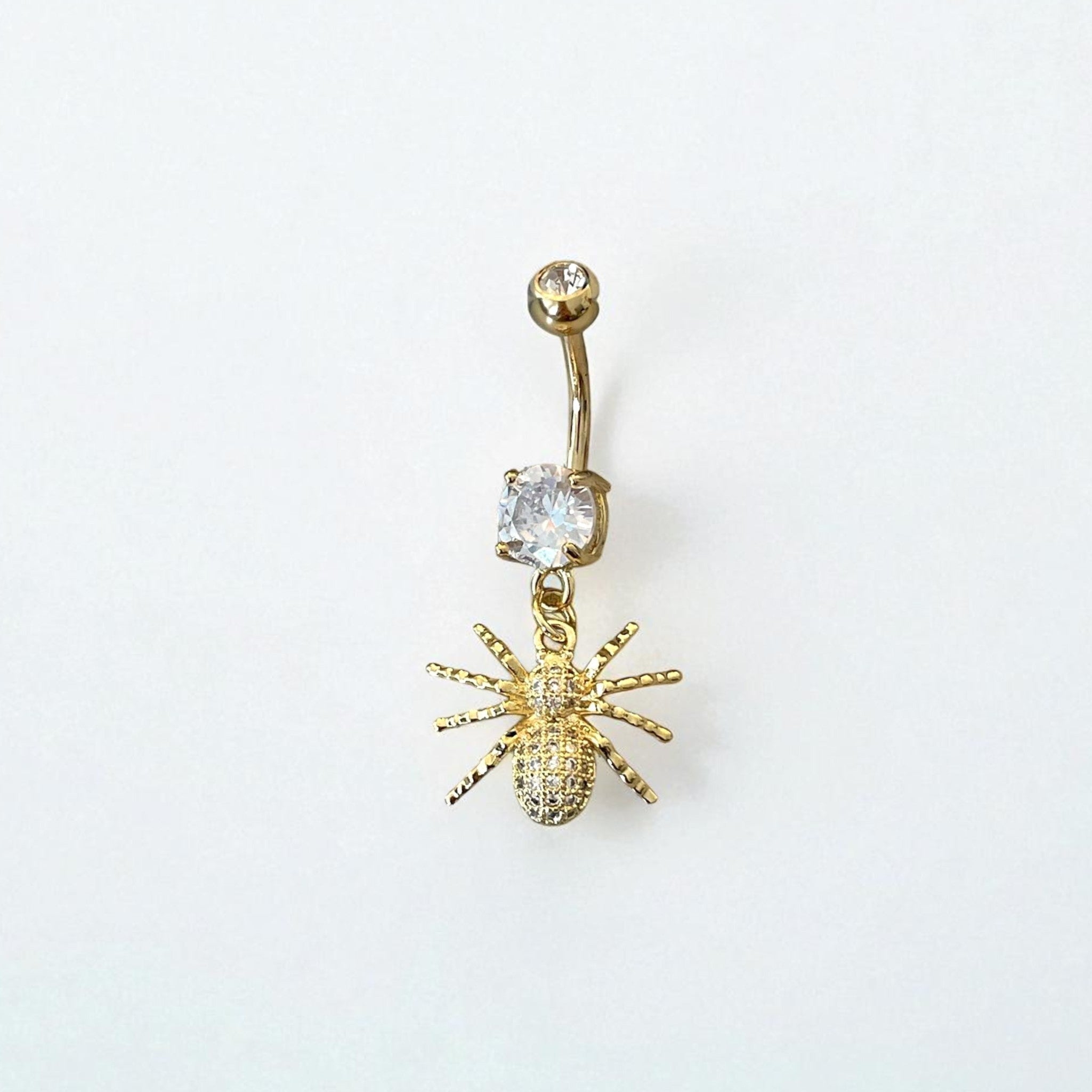 Gold belly button ring with spider design and clear gemstone on a white background