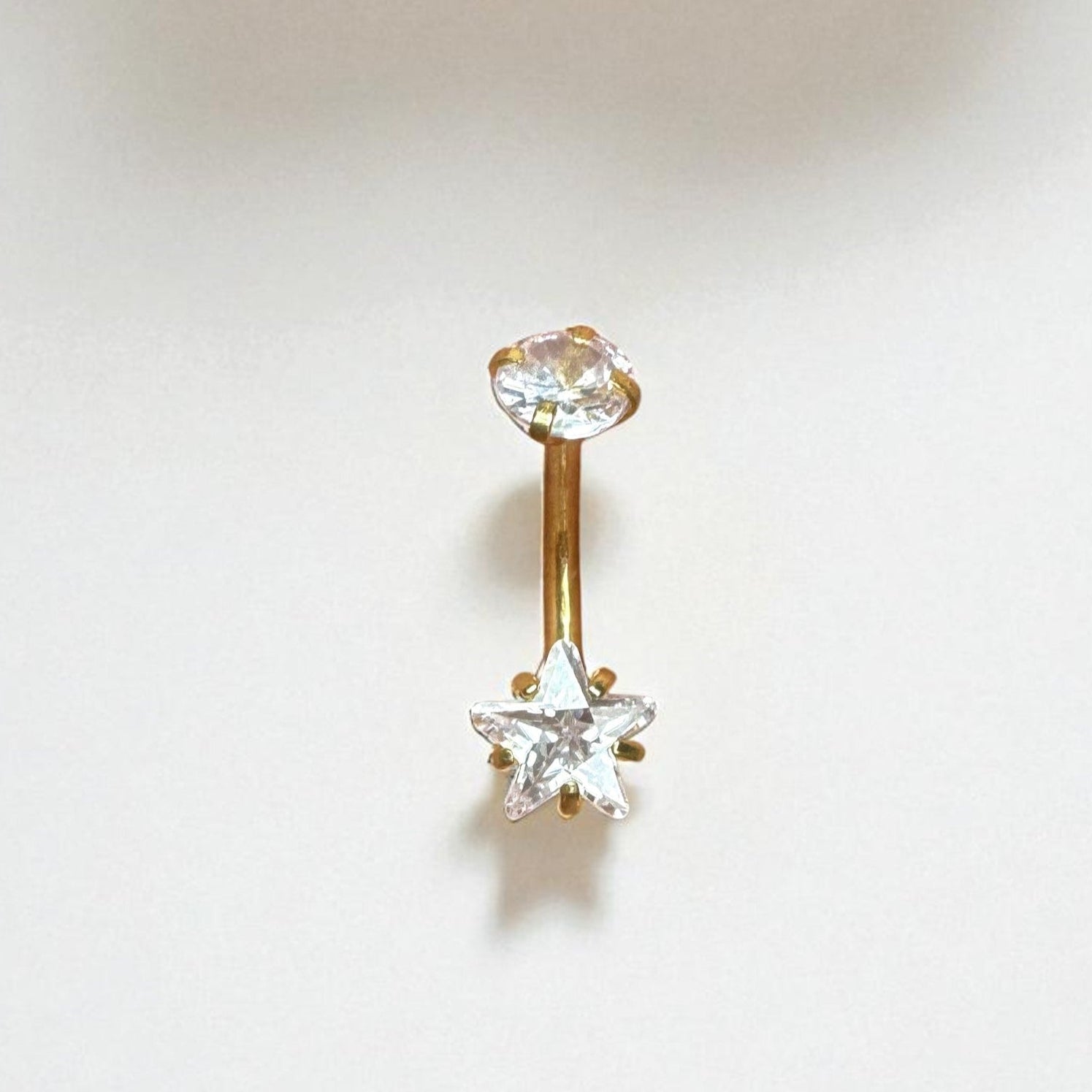 Gold belly button ring with a clear star CZ on a white background