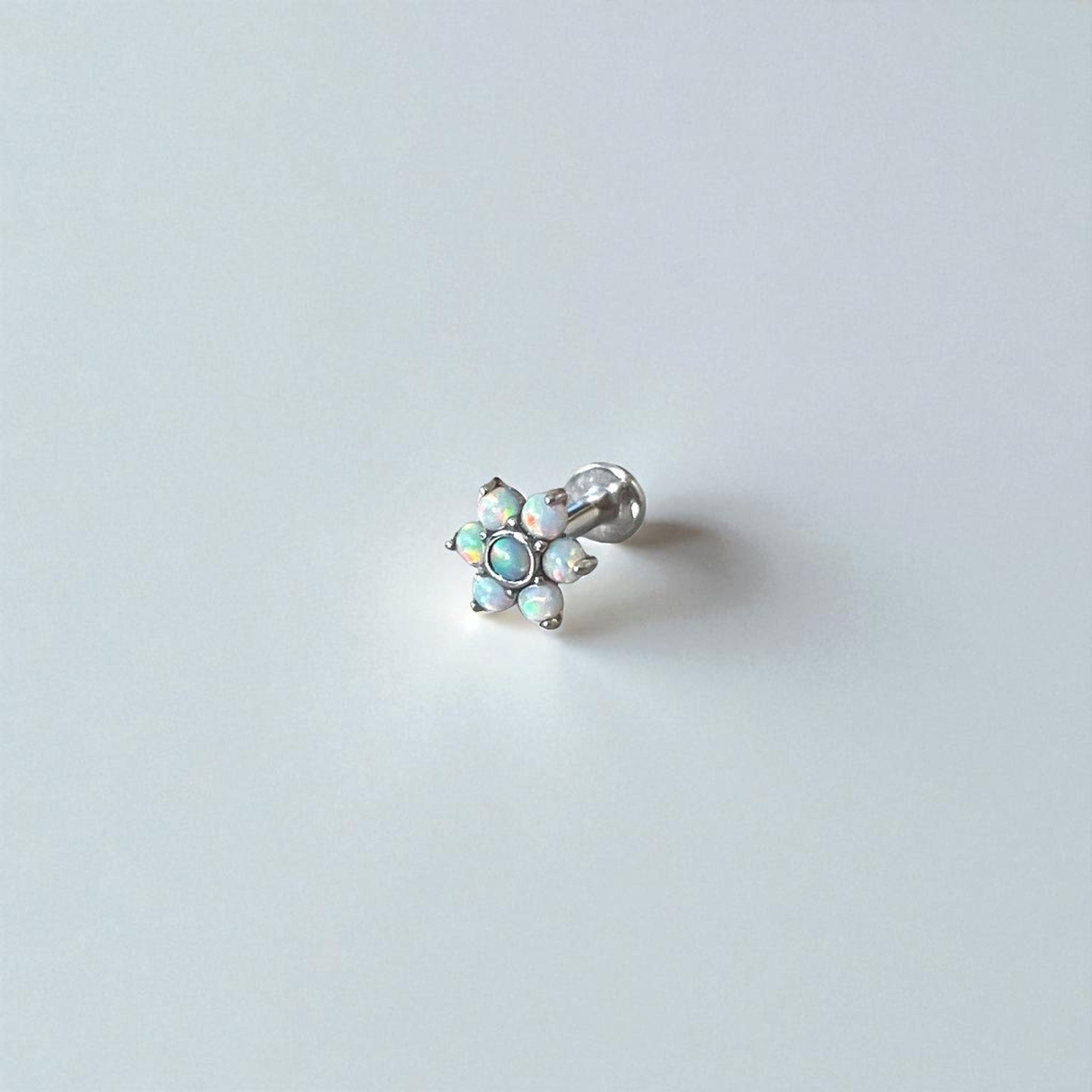 Silver earring with opal stones on a light gray background