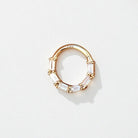 Gold hoop daith earring with clear baguette shaped gemstones on a light gray background