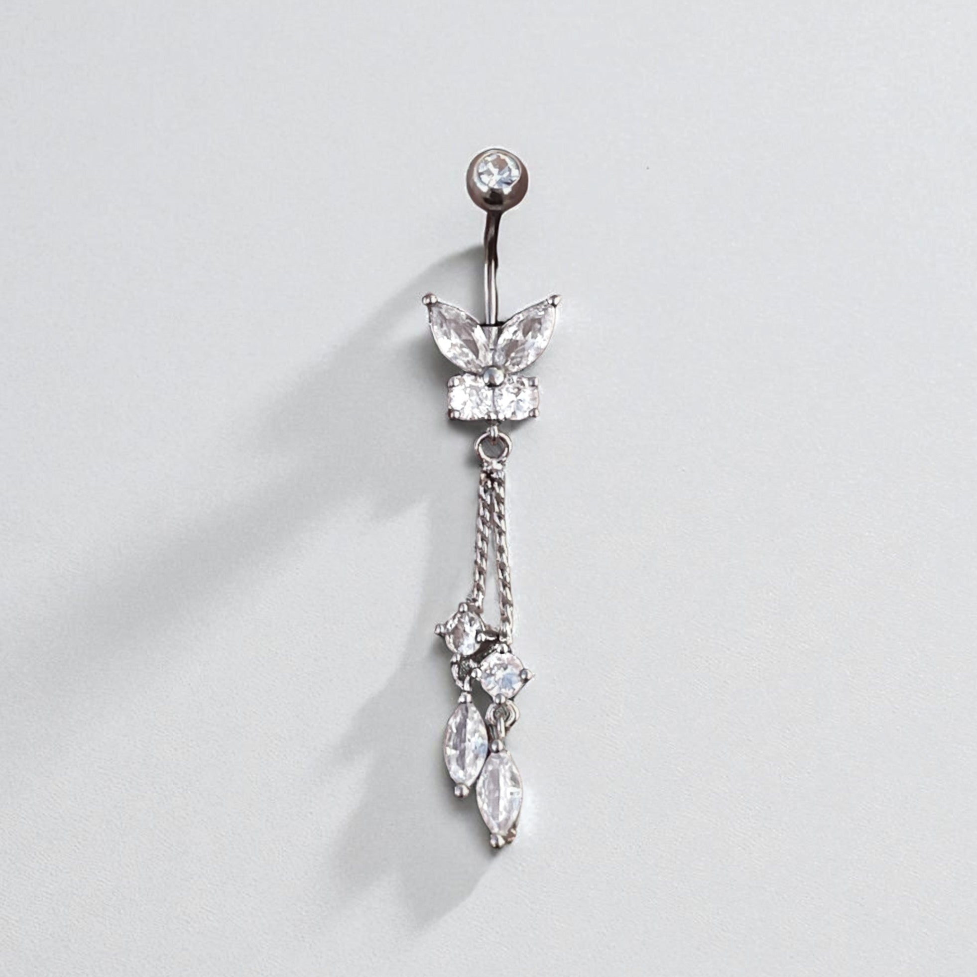 Butterfly-shaped belly button ring with dangling crystals on a light gray background