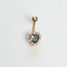 Gold belly button ring with a heart-shaped color shifting gem on a white background