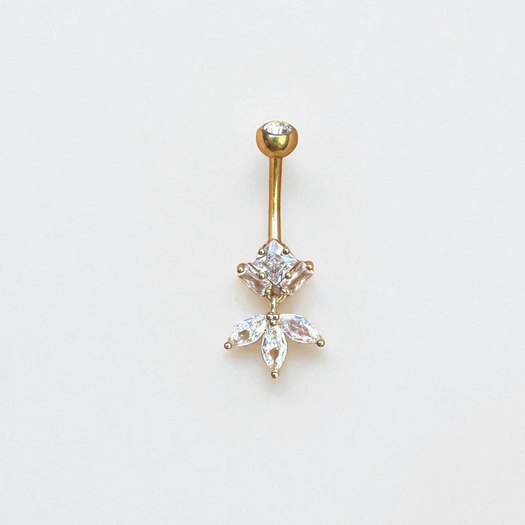 Gold belly button ring with gemstones on a light gray background