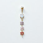 Gold belly button ring with floral designs and gemstones on a white background
