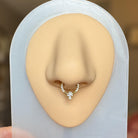 Elara Body Jewelry gold septum ring with pavé CZ stones and a central triangular and round CZ gem.